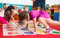 Cute toddlers playing in twister game at kindergarten