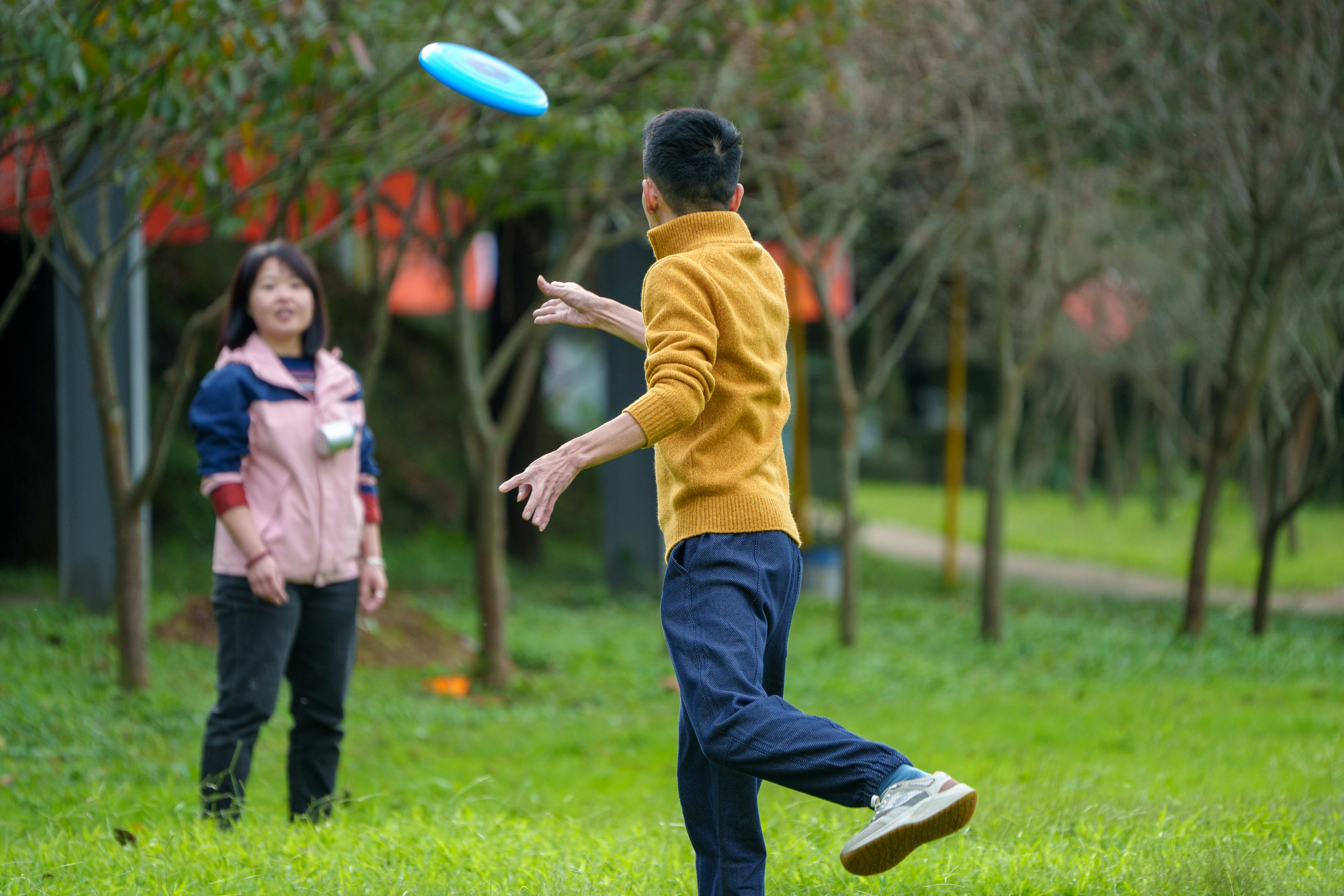 A man and a woman toss a frisbee in a park.