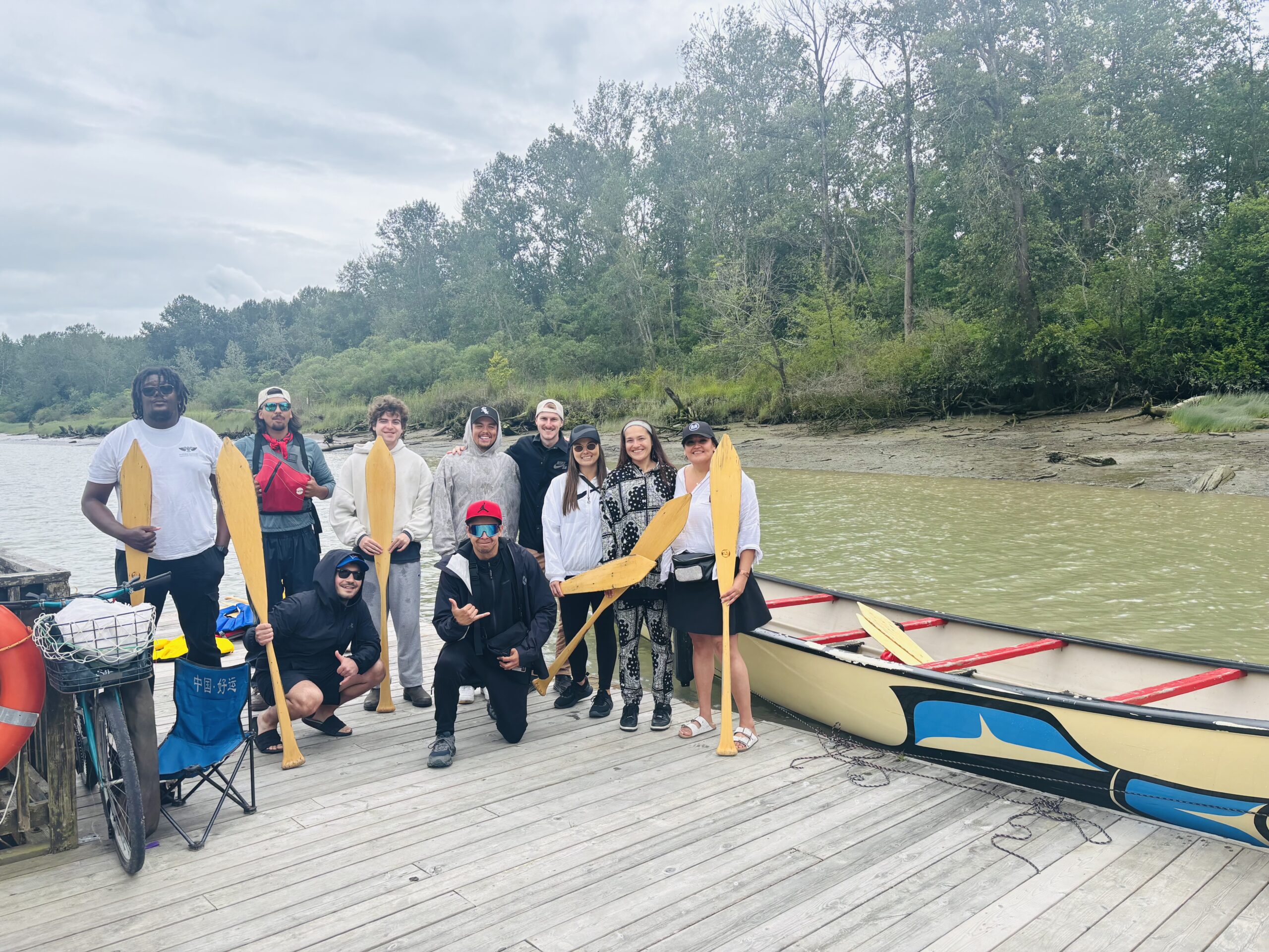 Group from Tsawassen First Nation standing on dock with canoe, ready for the water