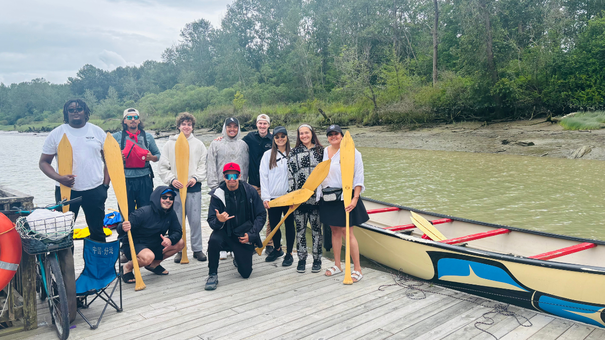 Group from Tsawassen First Nation standing on dock with canoe, ready for the water