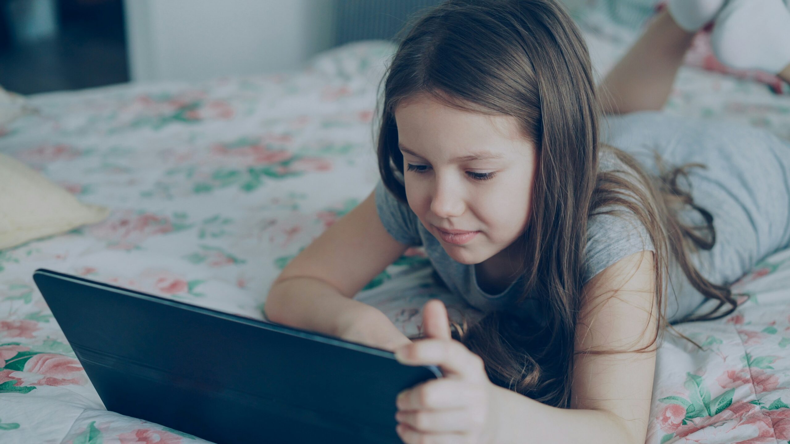 A young girl is pictured using a tablet.